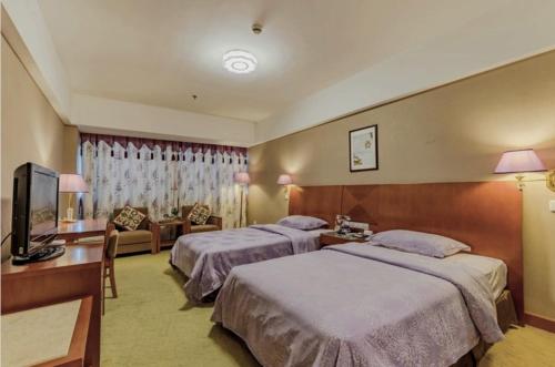 a hotel room with two beds and a television at Huangshan Tiandu International Hotel in Huangshan