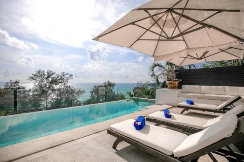 a pool with two lounge chairs and an umbrella at Surin Heights Villa in Surin Beach