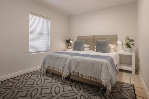 a white bedroom with a large bed and a window at Nguni River Apartment in Plettenberg Bay
