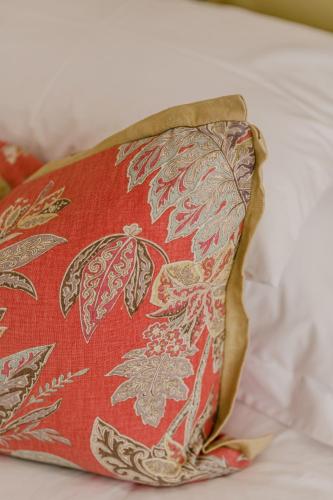 a red pillow with a floral pattern on a bed at Nguni River Apartment in Plettenberg Bay