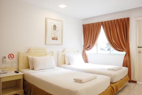 a hotel room with two beds and a window at Promenade Service Apartment in Kota Kinabalu