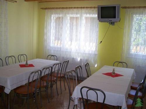 a room with two tables and chairs and a tv at Pensiunea Fenyő in Corund