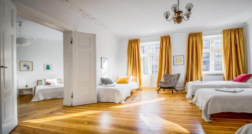 Cette chambre blanche comprend deux lits et une chaise. dans l'établissement Old Town Centrum Residence Apartments, à Poznań