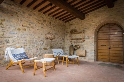 a patio with three chairs and a wooden door at Borgo Castello Panicaglia in Nocera Umbra