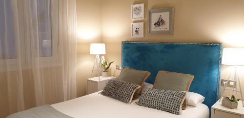 a bedroom with a bed with a blue headboard and two pillows at Arenal View by Forever Rentals in Bilbao