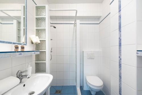 a white bathroom with a sink and a toilet at Plac Rybaków Inn in Sopot