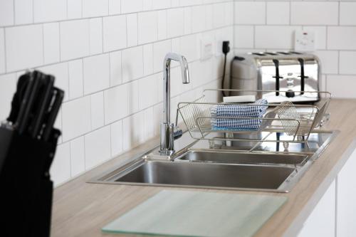 a kitchen sink with a dish drying rack next to it at Citystay - Devonshire Road in Cambridge