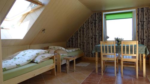 um quarto no sótão com 2 camas, uma mesa e cadeiras em Wieża Na Górce em Kunów