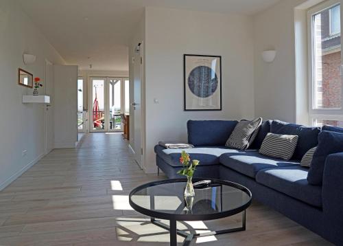 a living room with a blue couch and a glass table at Weiße Düne Ferienwohnung *Weiße Düne 9 / Gen Norden* in Wittdün