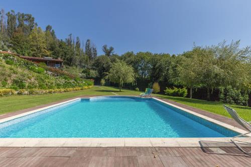 a swimming pool in a yard with two chairs at Host Wise - Boutique Country House w Pool in Travanca
