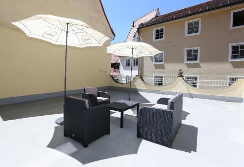 a patio with chairs and a table and umbrella at Arthotel ANA Goggl in Landsberg am Lech