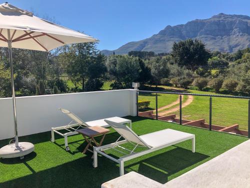 a patio with two chairs and a table and an umbrella at Rest at Chabivin in Stellenbosch