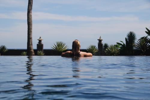 a woman sitting in the water in a swimming pool at Villa Cantik in Lovina