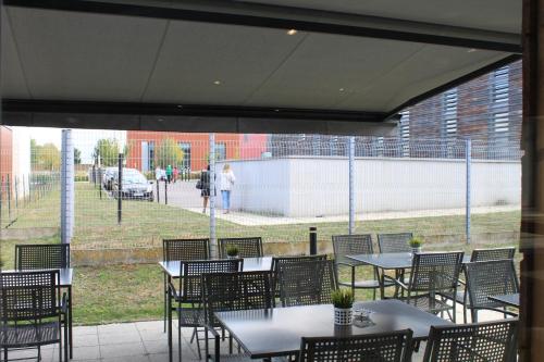 a patio with tables and chairs with a view of a park at ibis budget Metz Technopole in Metz