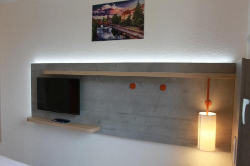 a living room with a flat screen tv and a lamp at ibis budget Metz Technopole in Metz