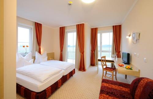 a hotel room with a bed and a desk and window at Hotel Inspiration Garni in Tittmoning