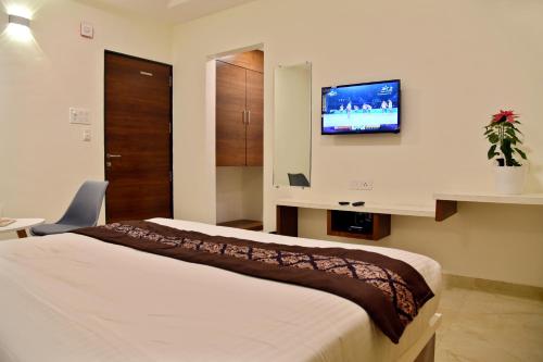 a bedroom with a bed and a tv on the wall at Hotel Grand Ecotel, Aurangabad in Aurangabad