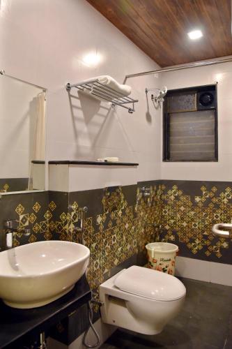a bathroom with a white toilet and a sink at Hotel Grand Ecotel, Aurangabad in Aurangabad