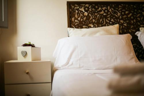 a bed with white sheets and a plant on a night stand at Casali Marchigiani - Ville vacanza private con piscina in Ostra