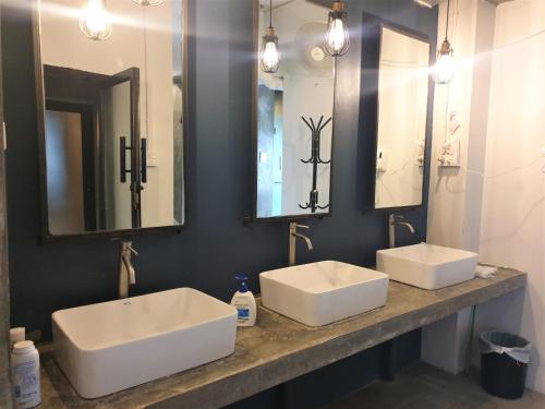 a bathroom with two sinks and two mirrors at Silom Space Hostel in Bangkok