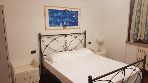 a bedroom with a bed with white sheets and a painting at Villetta G in Senigallia