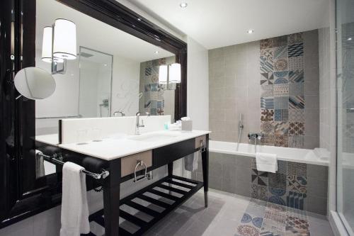 a bathroom with a sink and a tub at Park Hôtel Grenoble - MGallery in Grenoble