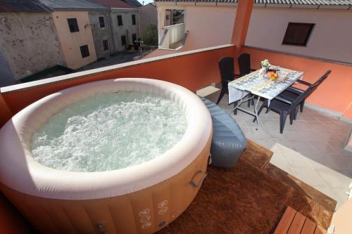 a hot tub on a roof with a table and chairs at MILKA APARTMANI POVLJANA in Povljana