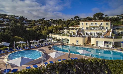 un complejo con una gran piscina con sillas y sombrillas en Althoff Hotel Villa Belrose en Saint-Tropez