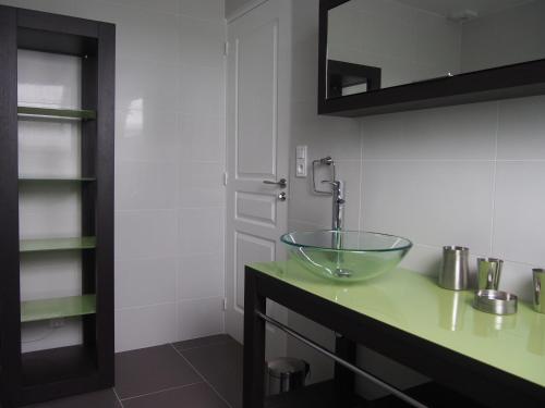 La salle de bains est pourvue d'un lavabo en verre sur un comptoir. dans l'établissement Maison Tombelaine, à Vains