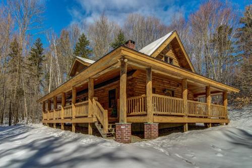 a log cabin in the snow in the woods at Sherman Log House in Ludlow
