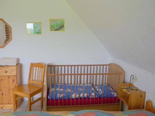 a nursery with a crib and a chair in a room at Hallmannshof in Sonsbeck