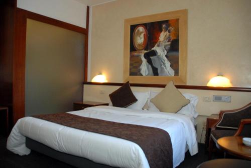 a hotel room with a bed and a painting on the wall at Green Hotel in Vergiate