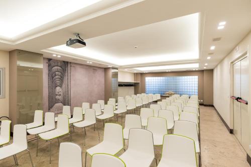 an empty room with white chairs and a projection screen at Hotel Dei Congressi in Rome