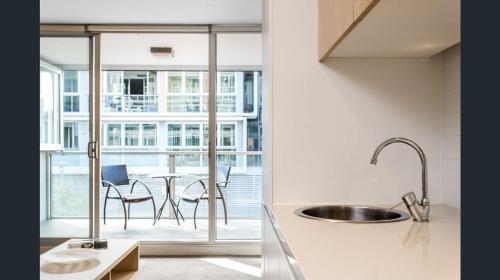 a kitchen with a sink and a table with chairs at Hi 5 star luxury Adelaide City Apartment in Adelaide