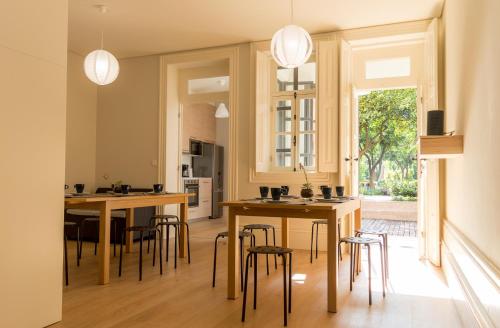 a kitchen with wooden tables and chairs in a room at Queen's Garden Hostel in Porto