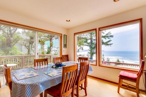 a dining room with a table and chairs and windows at Cliffside Serenity in Oceanside