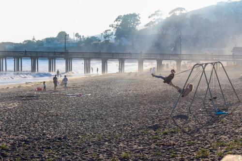 a group of people on a beach with a swing at Blue Door Retreat in Cayucos