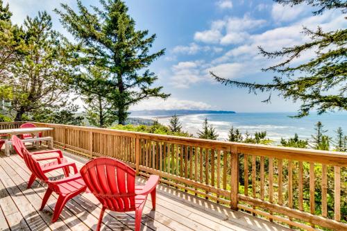 a deck with two red chairs and a table at Cliffside Serenity in Oceanside