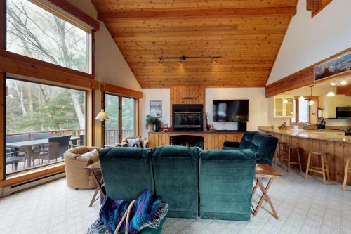 a living room with green chairs and a kitchen at South Hill Lodge in Ludlow