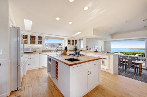 a kitchen with white cabinets and a view of the ocean at Harbour House in Bodega Bay
