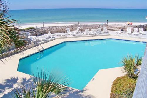 a large swimming pool with chairs and the beach at Barrier Dunes Hideaway in Oak Grove