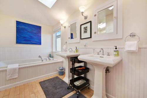 a white bathroom with two sinks and a tub and a bathtubermott at Harbour House in Bodega Bay