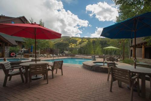 a patio with tables and umbrellas next to a pool at Trappers Crossing 8763 in Keystone