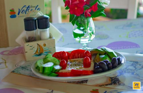 un plato de verduras en una mesa con un jarrón de flores en Oriental Bay en Palaiochóra