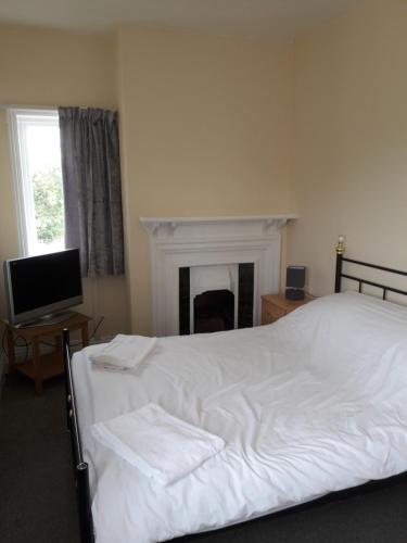 a bedroom with a white bed and a fireplace at Newton Brewery Inn in Middlewich