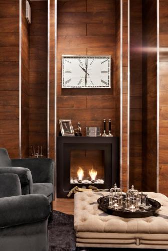 a living room with a fireplace and a clock on the wall at Tryp by Wyndham Luebeck Aquamarin in Lübeck
