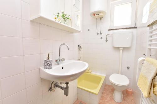 uma casa de banho branca com um lavatório e um WC em Apartments Brico em Primošten