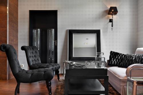 a living room with black chairs and a mirror at Tryp by Wyndham Luebeck Aquamarin in Lübeck