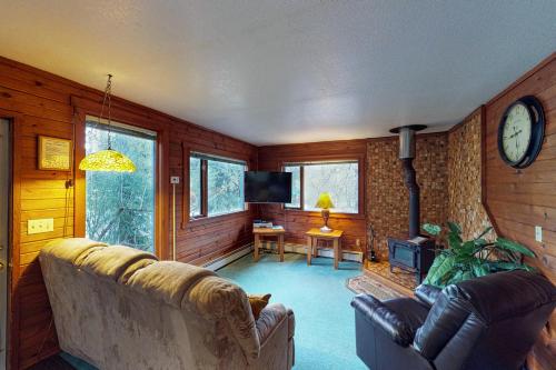a living room with a couch and a clock on the wall at Darwin's in Girdwood