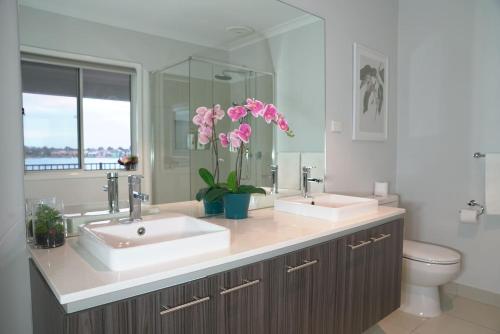 een badkamer met 2 wastafels en een toilet met roze bloemen bij Luxury Waterfront Villa in Sanctuary Lakes in Point Cook